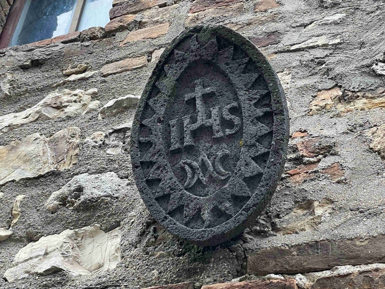 Simbolo dell'IHS nel sole radiante tra i vicoli di Montecchio in Umbria